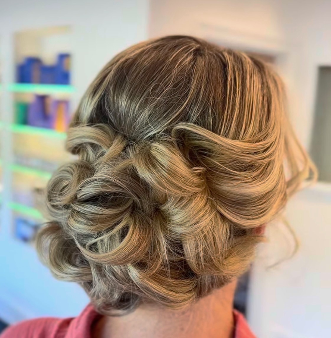 Blonde hair styled in a curled low updo by @erastylist.