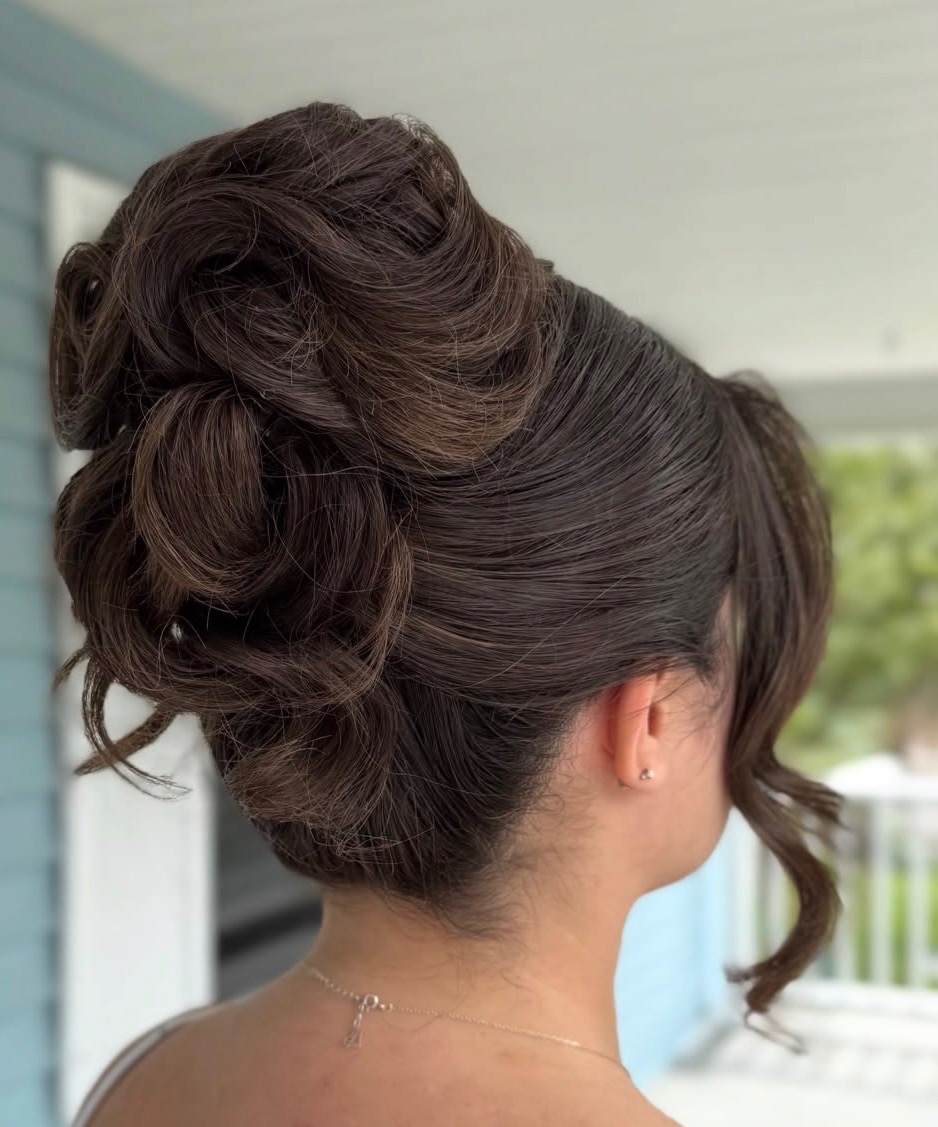 Dark hair styled in a textured high updo by @erastylist.